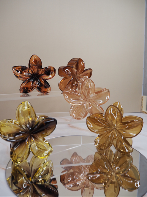 italienische mode kleiber werksverkauf Sortiment durchscheinender Haarspangen aus Harz mit Blumenmotiven in Braun- und Bernsteintönen.