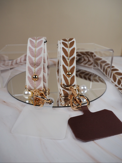 italienische mode kleiber werksverkauf Zwei elegante Schlüsselanhänger mit rosa und braunen Bändern mit Blattmuster und goldenen Akzenten.