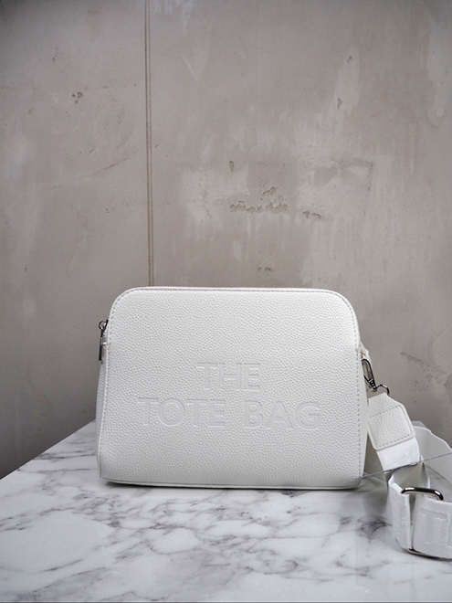 italienische mode kleiber werksverkauf Weiße Einkaufstasche aus Leder mit der Prägung „The Tote Bag“ auf der Vorderseite.