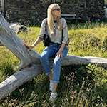 italienische mode kleiber werksverkauf Frau in stylischen italienischen Jeans und Pullover sitzt auf einem Baumstamm.