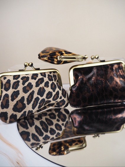 italienische mode kleiber werksverkauf Geldbörsen mit Leopardenmuster in verschiedenen Stilen, die sich auf einer verspiegelten Oberfläche spiegeln. Perfekte Modeaccessoires.