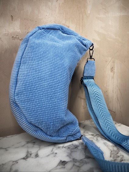 italienische mode kleiber werksverkauf Blaue Cord-Umhängetasche mit verstellbarem Riemen auf Marmoroberfläche, ein stilvolles Modeaccessoire.