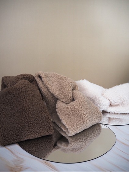 italienische mode kleiber werksverkauf Drei Teddybärtaschen in Braun, Beige und Weiß auf einer verspiegelten Oberfläche, perfekte Wintermode.