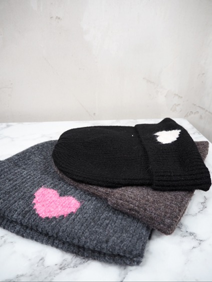 italienische mode kleiber werksverkauf Drei warme gestrickte Wintermützen, darunter eine graue mit rosa Herz und eine schwarze mit weißem Herz.