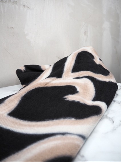 italienische mode kleiber werksverkauf Schwarz-beige gemusterter Winterschal auf Marmoroberfläche.