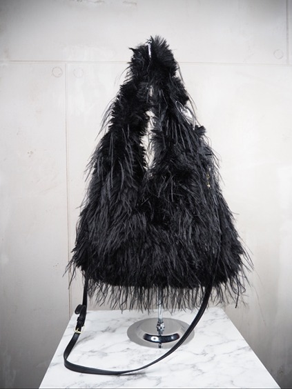 italienische mode kleiber werksverkauf Schwarze Federhandtasche auf einem Marmortisch, eine luxuriöse Umhängetasche