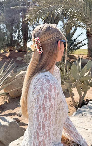 italienische mode kleiber werksverkauf Frau mit blondem Haar, das von einem roten und weißen Haarspange gehalten wird, die auf einem Felsen sitzt