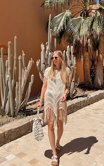 italienische mode kleiber werksverkauf Frau im Boho-Kleid mit Fransen und Makramee-Tasche vor Kakteen und Palmen