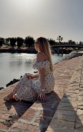 italienische mode kleiber werksverkauf Frau im Polka-Dot-Kleid sitzt am Wasser mit Tasche