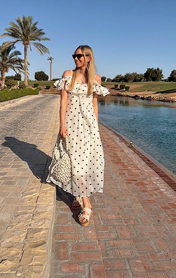 italienische mode kleiber werksverkauf Frau in weißem Kleid mit Punkten geht neben einem Teich