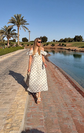italienische mode kleiber werksverkauf Frau im Polka-Dot-Kleid spaziert am Wasser entlang
