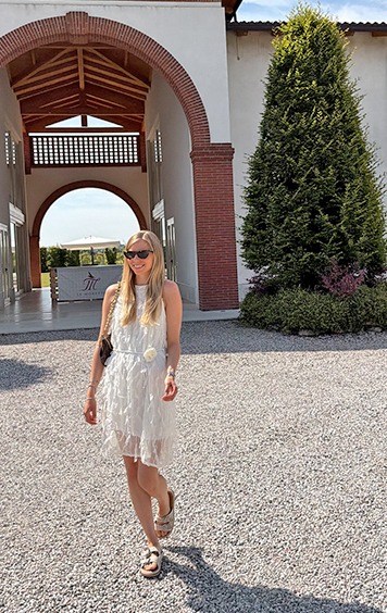 italienische mode kleiber werksverkauf Junge Frau in weißem Kleid und Sandalen vor italienischer Villa