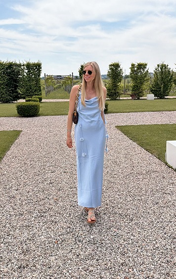 italienische mode kleiber werksverkauf Frau in blauem Kleid und Sandalen spaziert auf Kiesweg