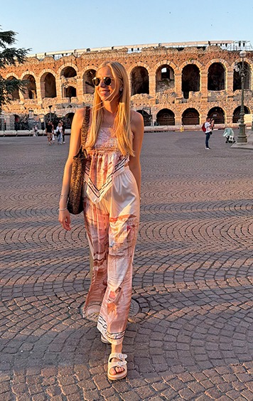 italienische mode kleiber werksverkauf Frau in einem gemusterten Jumpsuit spaziert vor dem Kolosseum in Rom