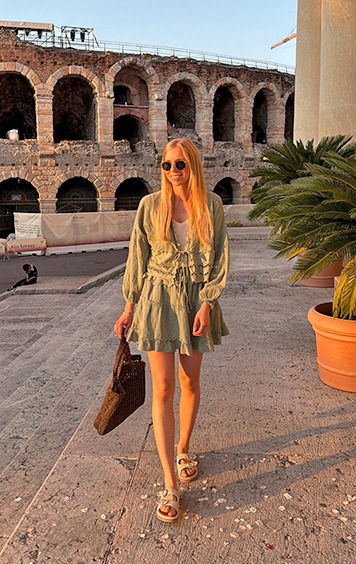 italienische mode kleiber werksverkauf Frau in Sommerkleid spaziert vor römischem Amphitheater in Italien