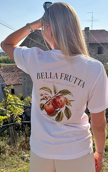 italienische mode kleiber werksverkauf Frau trägt weißes T-Shirt mit Pfirsich-Print „Bella Frutta“
