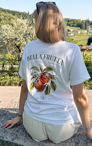 italienische mode kleiber werksverkauf Frau trägt T-Shirt mit Pfirsich-Print und italienischem Schriftzug "Bella Frutta