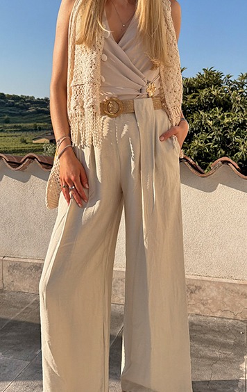 italienische mode kleiber werksverkauf Frau in beiger Hose und Weste mit Blumen-Brosche