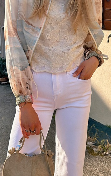 italienische mode kleiber werksverkauf Frau in weißer Hose und bedruckter Bluse mit Blumenmuster-Detail