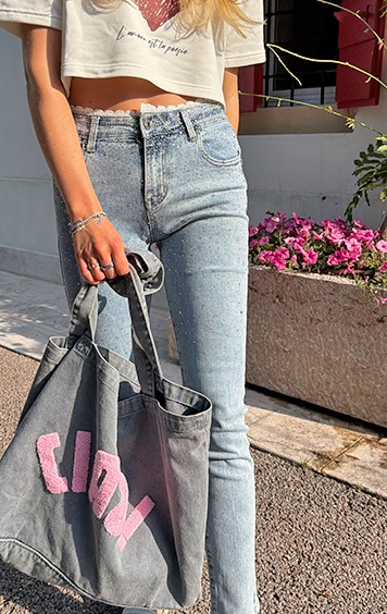 italienische mode kleiber werksverkauf Frau in funkelnder Jeans und Crop-Top mit Tasche