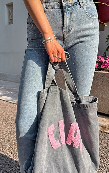 italienische mode kleiber werksverkauf Frau mit glitzernder Jeans und grauer Tasche mit pinker Schrift