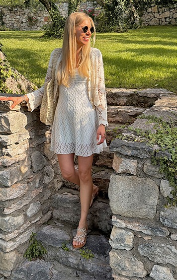 italienische mode kleiber werksverkauf Frau in weißem Kleid und Strickjacke auf Steintreppe im Garten