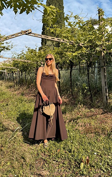 italienische mode kleiber werksverkauf Frau in braunem Kleid und Sonnenbrille in einem Weinberg.