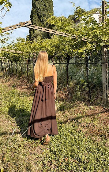 italienische mode kleiber werksverkauf Frau in braunem Kleid spaziert durch einen Weinberg