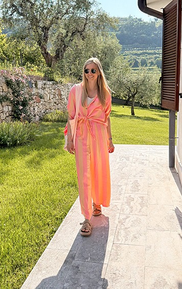 italienische mode kleiber werksverkauf Frau in gestreiftem Sommeranzug geht auf sonniger Terrasse