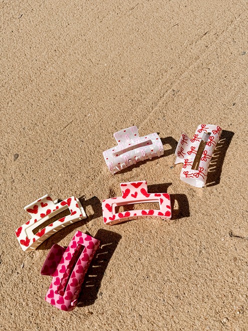 italienische mode kleiber werksverkauf Mehrere Haarspangen mit Herz- und Schleifenmuster auf Sand