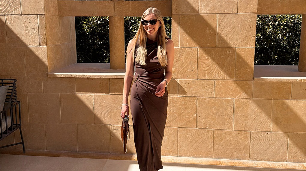 italienische mode kleiber werksverkauf Frau in braunem Kleid und Sonnenbrille steht vor Steinmauer