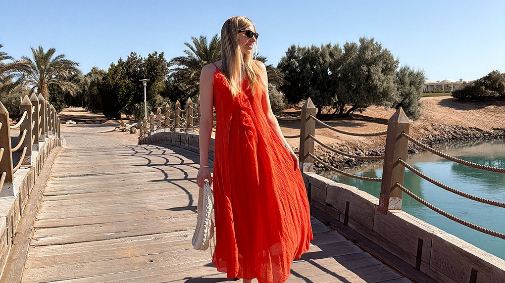 italienische mode kleiber werksverkauf Frau in rotem Sommerkleid auf Holzsteg am Wasser