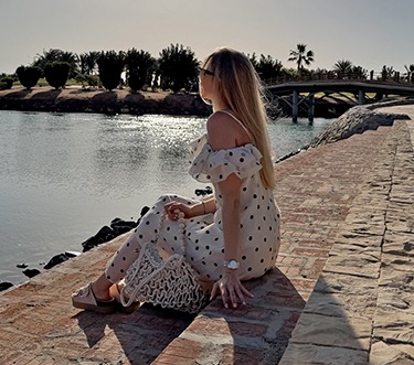 italienische mode kleiber werksverkauf Frau in Polka-Dot-Kleid genießt die Sonne am Wasser