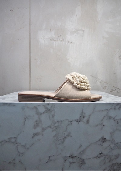 italienische mode kleiber werksverkauf Beige Ledersandale mit gehäkeltem Blumendetail auf Marmortisch
