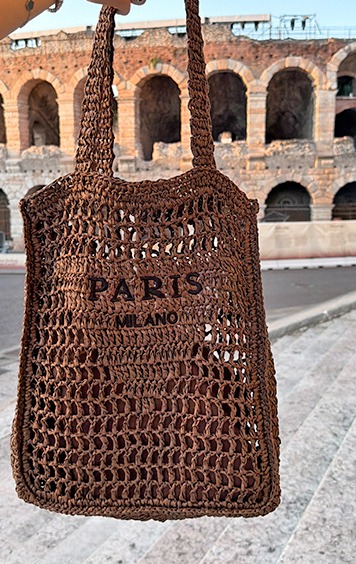 italienische mode kleiber werksverkauf Braune gehäkelte Tasche mit "PARIS MILANO" Aufschrift vor antiker Arena