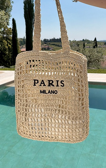 italienische mode kleiber werksverkauf Strohtasche mit Aufschrift "PARIS MILANO" über einem Pool