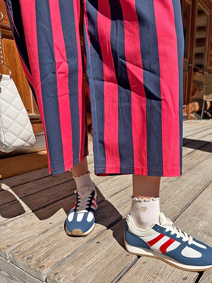 italienische mode kleiber werksverkauf Person in rot-blauen Streifen-Hose und Retro-Sneakern auf Holzsteg
