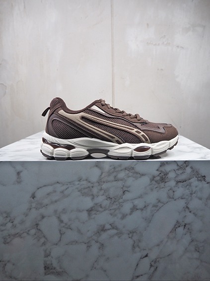 italienische mode kleiber werksverkauf Brauner Herren-Sneaker mit weißer Sohle auf Marmortisch