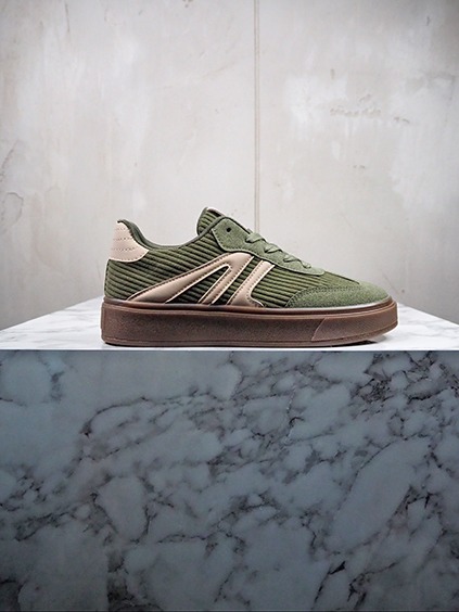 italienische mode kleiber werksverkauf Grüner Sneaker mit beigen Akzenten auf Marmorunterlage