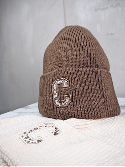 italienische mode kleiber werksverkauf Braune Strickmütze mit Leopardenmuster "C"-Patch und eine cremefarbene Mütze daneben.