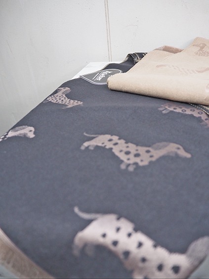 italienische mode kleiber werksverkauf Dunkelgraue Decke mit Dackel-Hundemuster, daneben eine beige Decke.