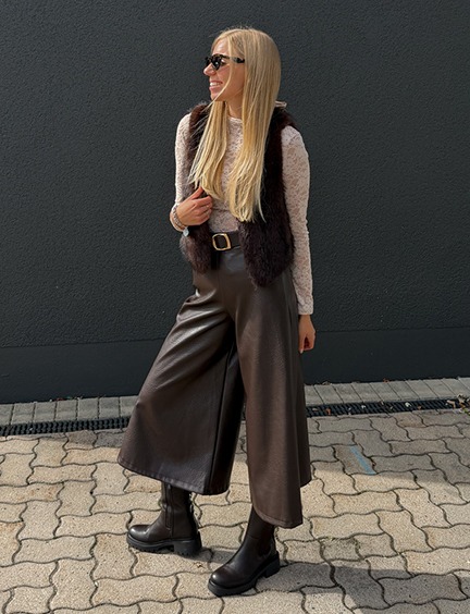 italienische mode kleiber werksverkauf Frau in brauner Lederhose, weißem Shirt und Weste im Herbst-Outfit