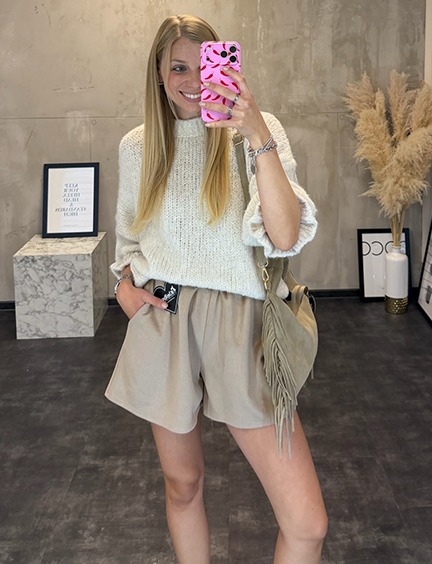 italienische mode kleiber werksverkauf Frau im beigen Outfit mit Pullover und Shorts, lächelnd in die Kamera