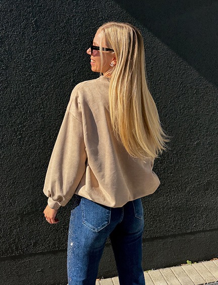 italienische mode kleiber werksverkauf Frau mit blonden Haaren in beigem Sweatshirt und Jeans mit Glitzer