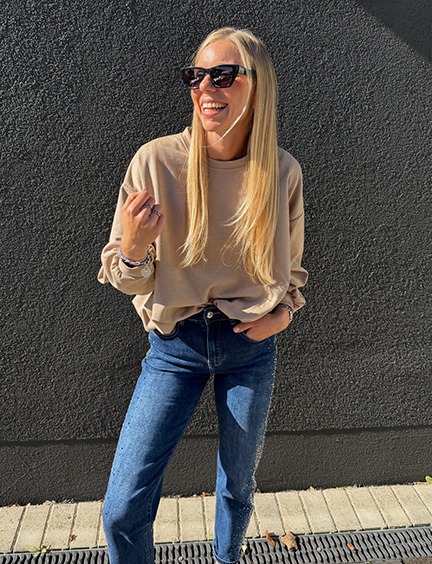 italienische mode kleiber werksverkauf Blonde Frau in beiger Sweatshirt und Jeans mit Strasssteinen