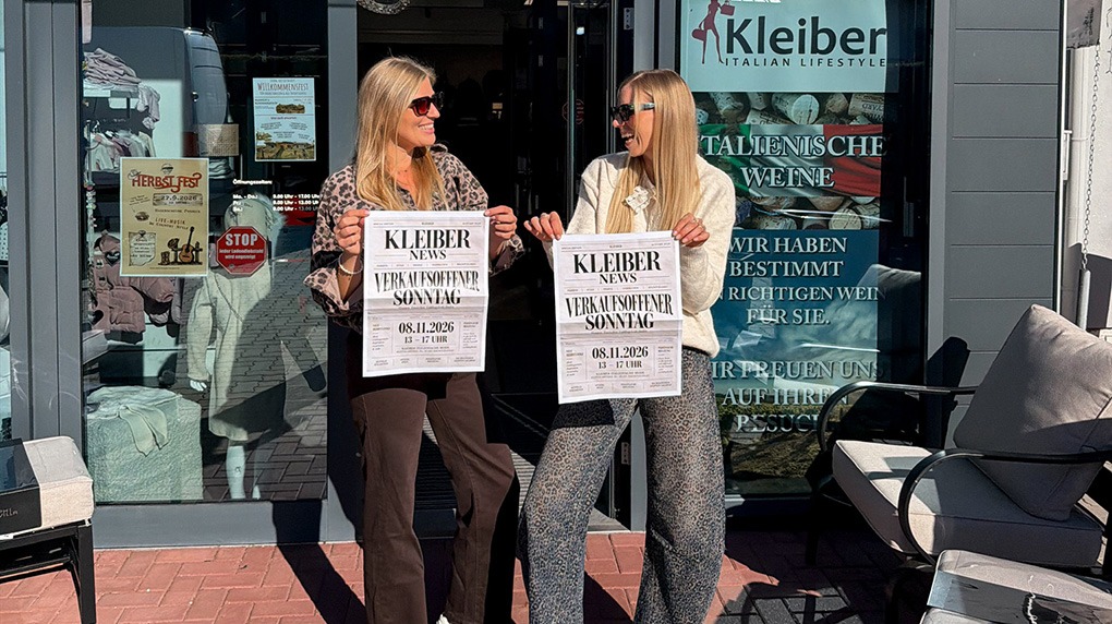 italienische mode kleiber werksverkauf Zwei Frauen halten "Kleiber News" Zeitungen vor einem Geschäft mit italienischen Lifestyle-Produkten.