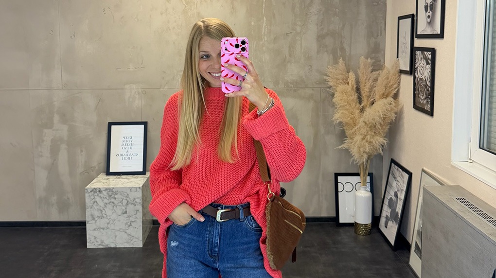 italienische mode kleiber werksverkauf Frau im roten Pullover und Jeans macht Selfie mit Handy